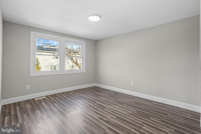 spare room with visible vents, baseboards, and dark wood finished floors