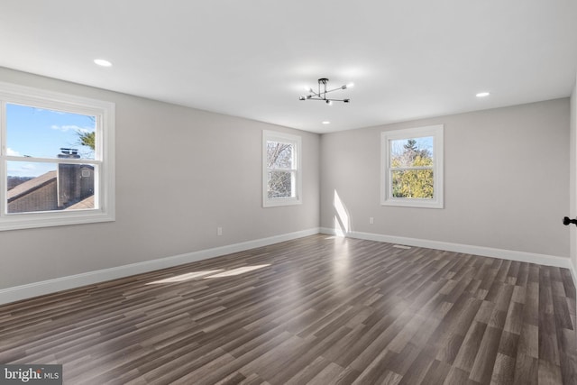 empty room featuring recessed lighting, an inviting chandelier, dark wood-type flooring, and baseboards
