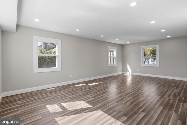 empty room with dark wood finished floors, recessed lighting, and baseboards