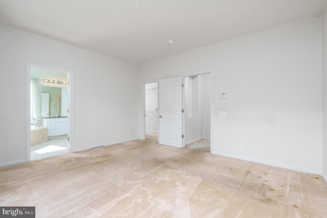 unfurnished bedroom featuring a spacious closet, carpet flooring, baseboards, and connected bathroom