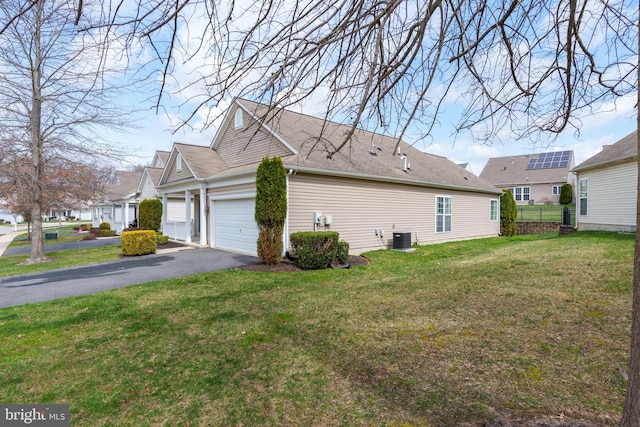 view of side of property with aphalt driveway, an attached garage, fence, a yard, and cooling unit