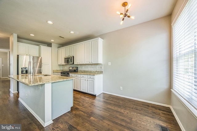 kitchen featuring decorative backsplash, a sink, appliances with stainless steel finishes, and a wealth of natural light