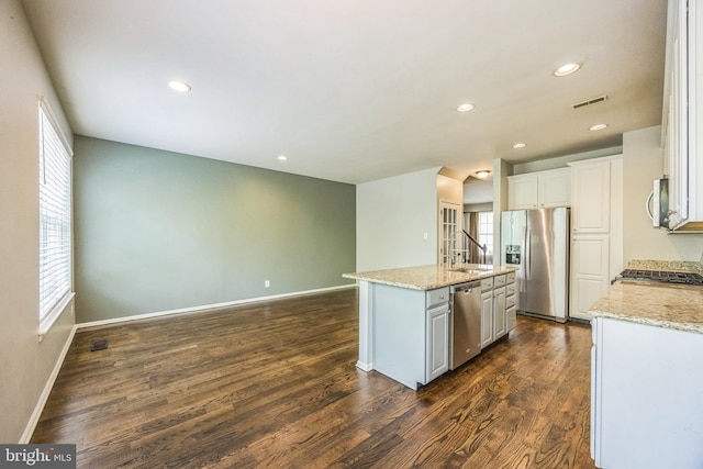 kitchen featuring visible vents, appliances with stainless steel finishes, a center island with sink, a sink, and baseboards
