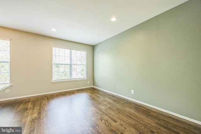 unfurnished room with plenty of natural light, recessed lighting, dark wood finished floors, and baseboards
