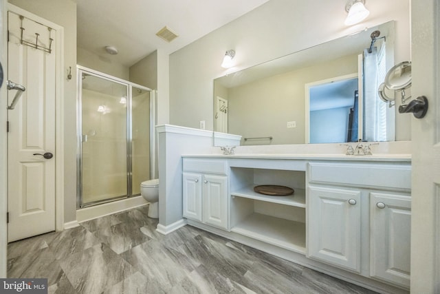 bathroom with double vanity, a stall shower, a sink, and visible vents