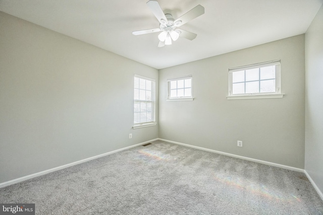 carpeted spare room with baseboards, a ceiling fan, and visible vents