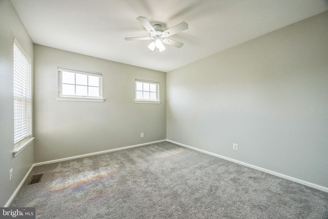 carpeted empty room featuring baseboards, ceiling fan, and visible vents