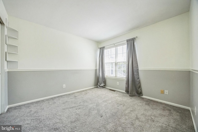 carpeted spare room featuring baseboards and visible vents