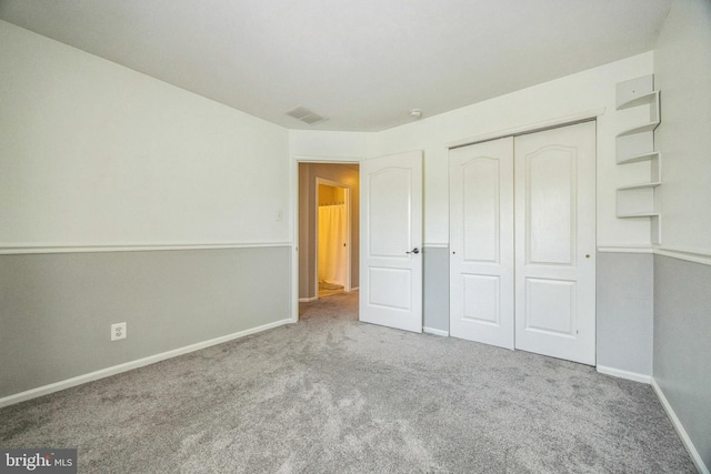 unfurnished bedroom with baseboards, carpet, a closet, and visible vents