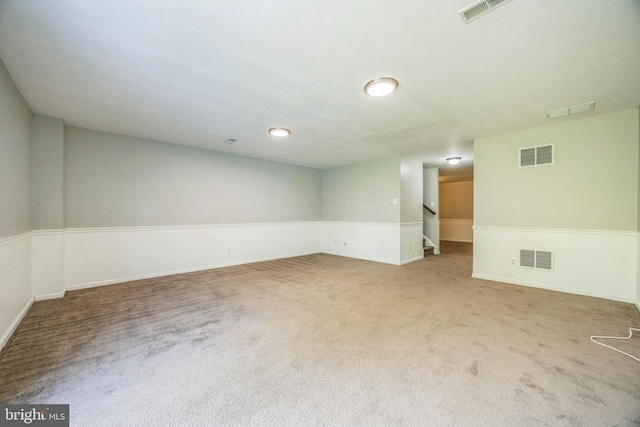 carpeted empty room with baseboards, visible vents, and stairway
