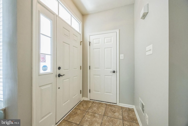 foyer featuring baseboards and light tile patterned flooring