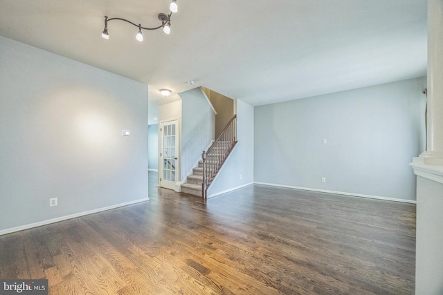 unfurnished living room featuring stairway, baseboards, and wood finished floors