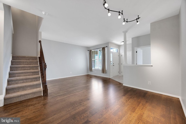 unfurnished living room with stairs, baseboards, and wood finished floors