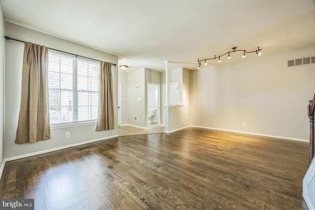 empty room with baseboards, wood finished floors, and visible vents