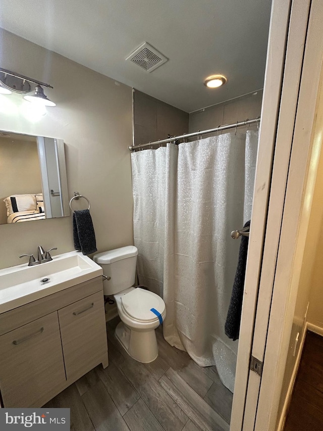 full bathroom featuring visible vents, toilet, vanity, and wood finished floors