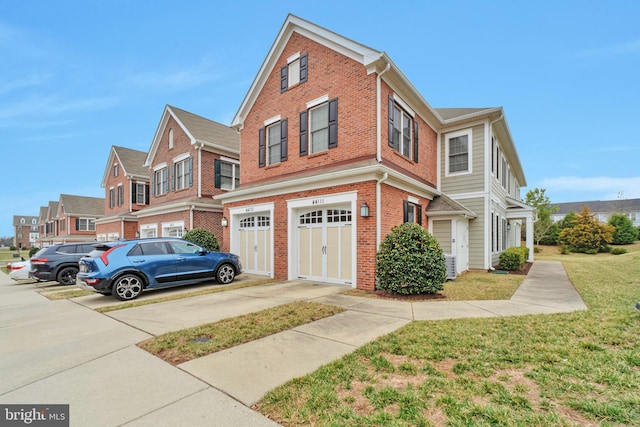 view of property featuring brick siding, an attached garage, driveway, and a front yard