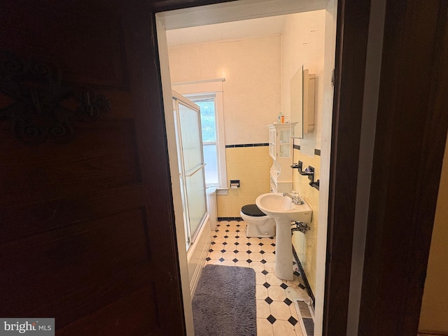 bathroom featuring visible vents, a sink, wainscoting, tile walls, and a shower with door