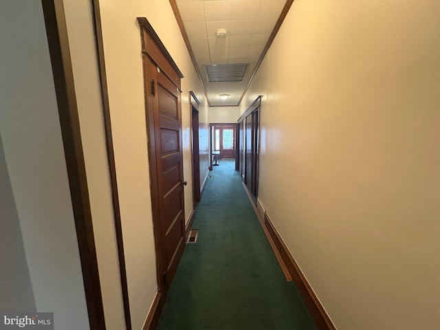 corridor featuring baseboards, visible vents, and dark carpet