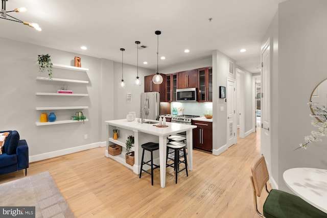 kitchen with open shelves, stainless steel microwave, freestanding refrigerator, a breakfast bar area, and light countertops