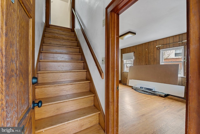 stairway featuring wood finished floors and wood walls