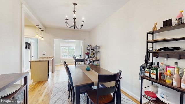 dining space featuring baseboards, an inviting chandelier, and light wood-style flooring
