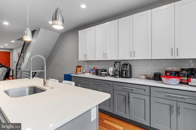 2714 W Jefferson St, Philadelphia, PA 19121 - kitchen with gray cabinetry, light wood-style flooring, pendant lighting, a sink, and decorative backsplash