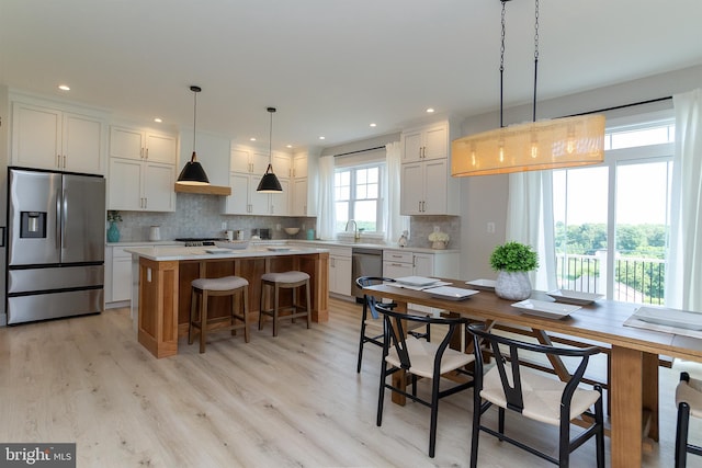kitchen featuring a kitchen island, a breakfast bar area, light countertops, appliances with stainless steel finishes, and white cabinetry
