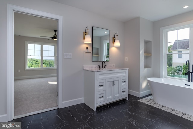 full bath with vanity, baseboards, a wealth of natural light, and a freestanding bath