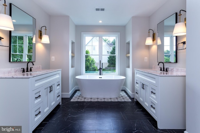 bathroom featuring a sink, baseboards, and two vanities