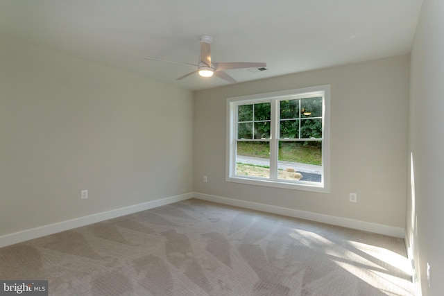 empty room featuring baseboards, light carpet, and ceiling fan