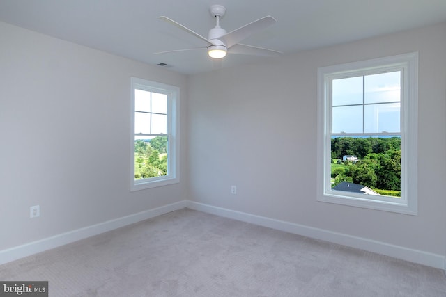 empty room with visible vents, a ceiling fan, baseboards, and light carpet