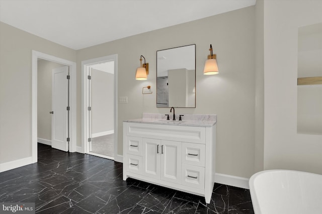bathroom with baseboards, a freestanding bath, marble finish floor, and vanity