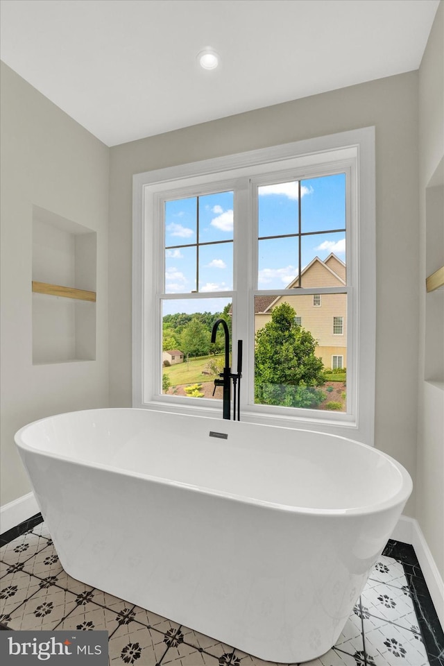 full bath featuring a soaking tub, built in features, recessed lighting, and baseboards