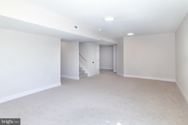 finished basement featuring light colored carpet, stairway, baseboards, and visible vents