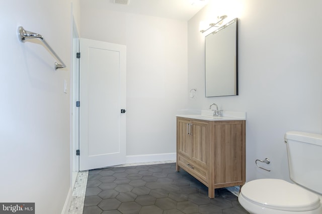 bathroom with vanity, toilet, and baseboards