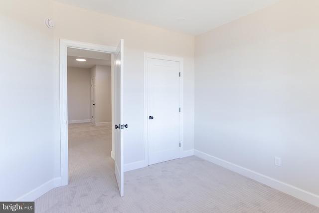 unfurnished bedroom featuring light carpet and baseboards
