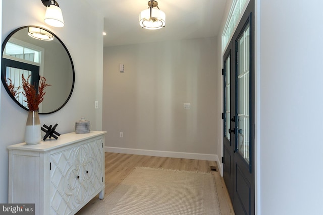 foyer entrance featuring light wood finished floors, visible vents, and baseboards