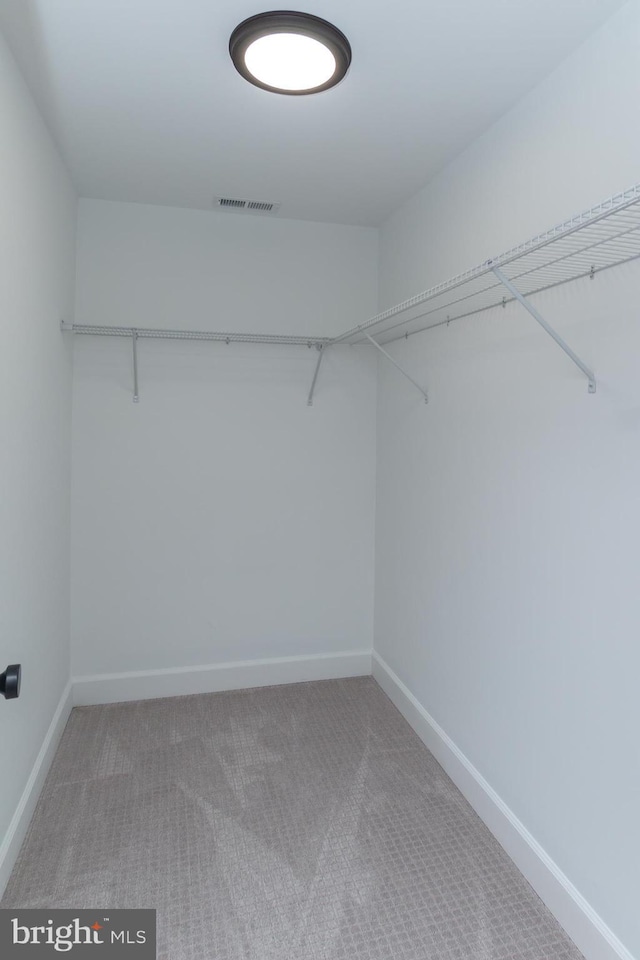 walk in closet with visible vents and light carpet