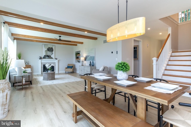 dining room featuring stairway, wood finished floors, a ceiling fan, baseboards, and beamed ceiling