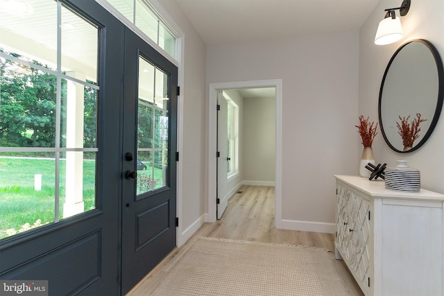 doorway to outside featuring a healthy amount of sunlight, light wood-type flooring, and baseboards