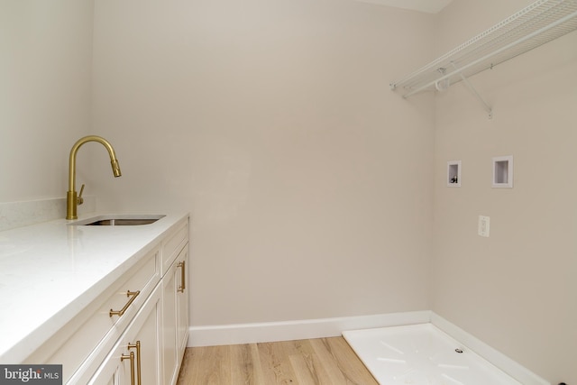 clothes washing area featuring washer hookup, light wood-type flooring, baseboards, and a sink