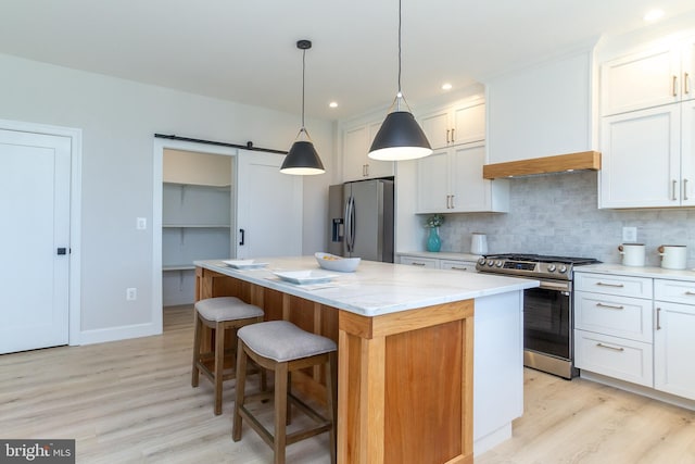kitchen featuring premium range hood, a kitchen island, backsplash, light wood-style floors, and appliances with stainless steel finishes