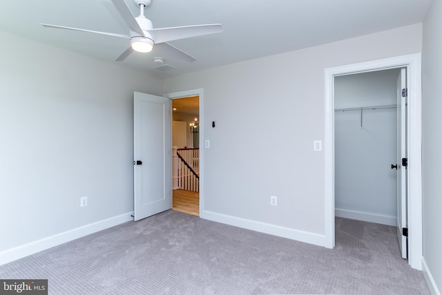 unfurnished bedroom featuring carpet, baseboards, ceiling fan, a spacious closet, and a closet