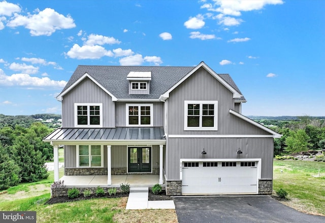 modern farmhouse style home with stone siding, a porch, driveway, and french doors