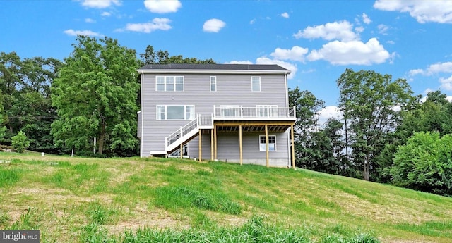 rear view of house with a lawn, stairs, and a deck