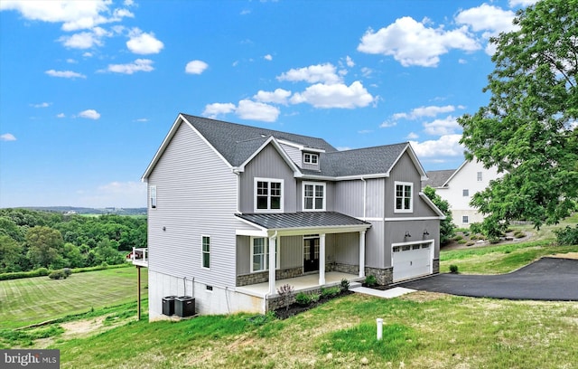 view of front of property with a front lawn, a garage, driveway, and metal roof