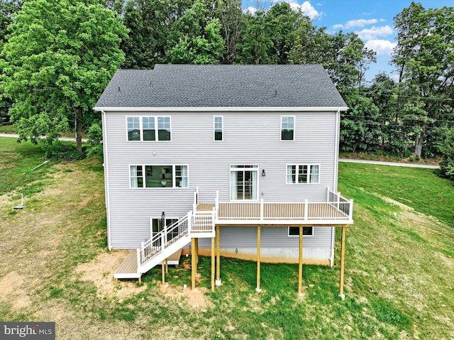 rear view of house featuring a wooden deck, a lawn, stairs, and a shingled roof