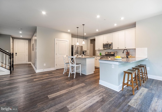 427 Whispering Elm Ln, Millersville, MD 21108 - kitchen with stainless steel appliances, a kitchen breakfast bar, baseboards, recessed lighting, and dark wood-type flooring