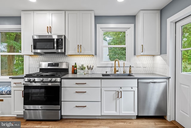 kitchen featuring decorative backsplash, white cabinets, appliances with stainless steel finishes, and a sink
