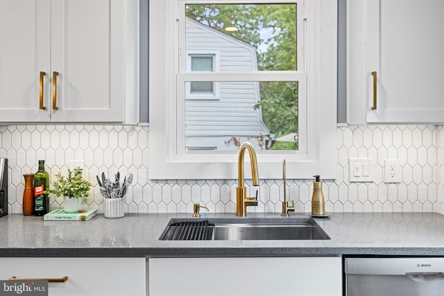 kitchen with dishwasher, white cabinets, light stone counters, and a sink
